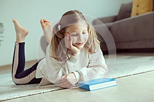 Portrait of cute teen girl reading book on floor in room at home