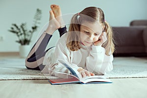 Portrait of cute teen girl reading book on floor in room at home