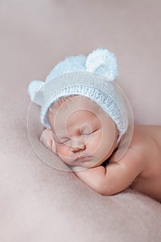 Portrait of cute ten days old newborn baby girl wearing bear bonnet with ears.