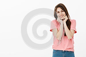 Portrait of cute and tender girlfriend in pink t-shirt, holding palms on jaw and smiling broadly being touched with