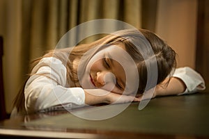 Portrait of cute tired schoolgirl sleeping on desk