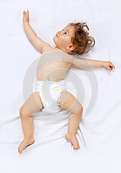 Portrait of cute toddler boy, baby in diaper calmly lying isolated over white studio background.