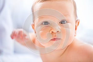 Portrait of cute toddler boy lying on bed. Newborn child in bedroom. Baby lies on his tummy and raises the head