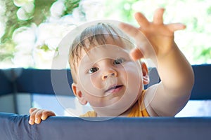 Portrait of a cute toddler boy playing in the playpen