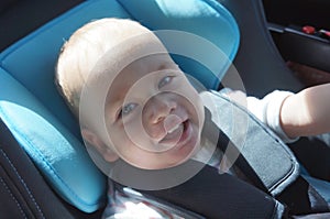 Portrait of cute toddler boy sitting in car seat. Child transportation safety