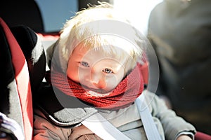 Portrait of cute toddler boy sitting in car seat. Child transportation safety