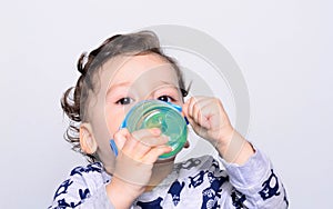 Portrait of a cute toddler drinking water from the bottle.