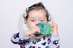 Portrait of a cute toddler drinking water from the bottle.