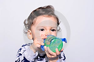 Portrait of a cute toddler drinking water from the bottle.