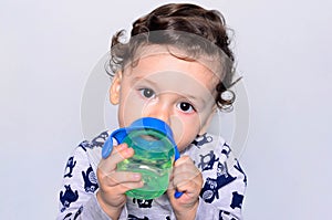 Portrait of a cute toddler drinking water from the bottle.