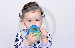 Portrait of a cute toddler drinking water from the bottle.