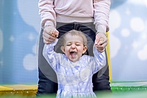 Portrait of a cute toddler girl holding mom`s hands and smiling happily and laughing closing her eyes. close-up, soft