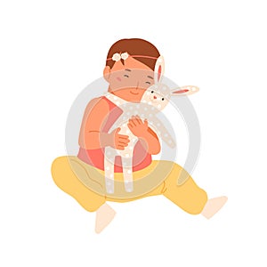 Portrait of cute toddler playing with textile rabbit toy. Little baby girl hugging lovely hare. Happy infant embracing