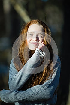 Portrait of twelve year old girl with fiery red hair posing in the pine park for a photoshoot