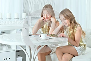 Portrait of cute twin sisters with modern magazine photo