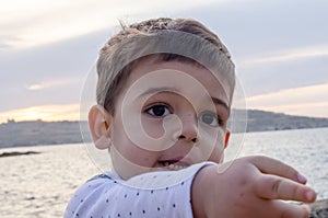 Portrait of cute two years old boy on the beach pointing finger to something close up