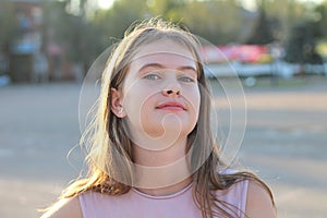 Portrait of a cute white teen girl on blurred summer green city background