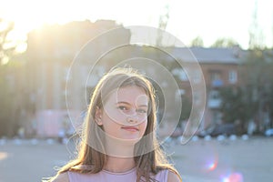 Portrait of a cute white teen girl on blurred summer green city background