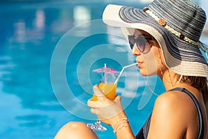 Portrait of cute woman enjoying fruit cocktail next to pool