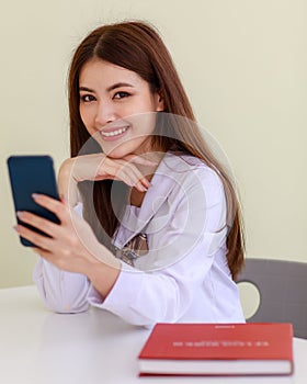 Portrait of cute and young Asian girl, Lao ethnicity, wearing Japanese, Korean style schoolgirl uniform sitting and playing