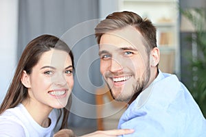 Portrait of cute young couple sitting in sofa.