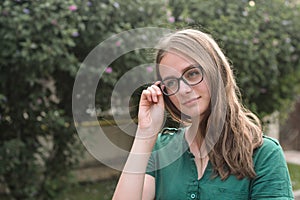 Portrait of cute young girl with eyeglasses, smiling. Blonde hair, natural, beautiful teen age girl. Summer portrait