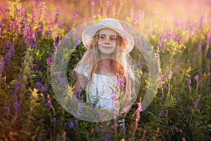 Portrait of cute young girl with long hair in a hat at sunset