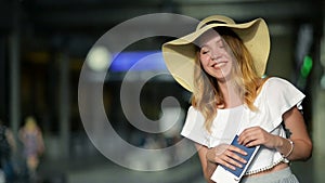 Portrait of Cute Young Girl in Summer Hat Holding Her Passport and Ticket at the Airport. Travelling Concept. Blurred