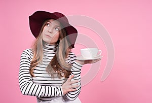 Portrait of a cute young lady in a fashionablea hat with a cup and saucer