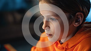 Portrait of a Cute Young Teenage Boy Being Concentrated on a Computer Screen in a Dark Cozy Room