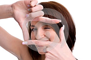 Portrait of cute young woman creates a frame with her hands