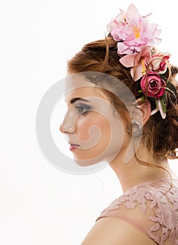 Portrait of cute young woman in delicate pink dress, professional hairstyle with wreath