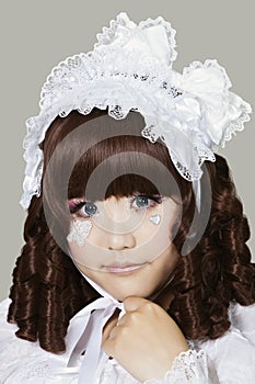 Portrait of cute young woman in doll costume over gray background