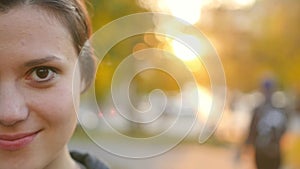 Portrait of a cute young woman enjoying autumn in the park during sunset. Brunette in autumn park on a background of