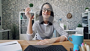 Portrait of cute young woman skyping in office talking waving hand sending kiss