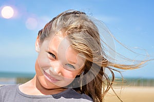 portrait of a pretty little girl with windy hair on the beach in summer