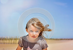 portrait of a pretty little girl with windy hair on the beach in summer