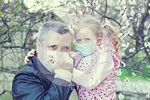 Portrait of dad and daughter in masks near a flowering tree