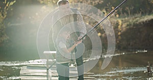 Portrait dad encouraged his son to fishing on lake at sunny day, spending good moments together.