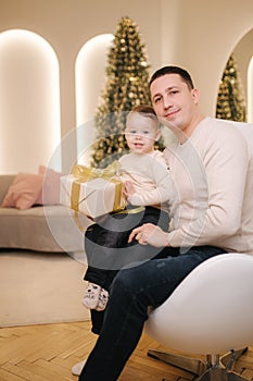 Portrait of dad and son in Christmas time. Happy family spent time together during the holiday. Boy give present to