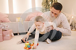 Portrait of dad and son in Christmas time. Happy family spent time together during the holiday. Boy play with toys with