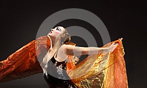 Portrait of a dancing young woman with flying fabric