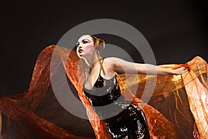 Portrait of a dancing young woman with flying fabric