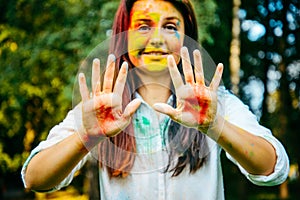 Portrait of dark long hair woman all in holi paints shows her palms