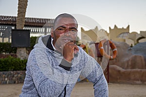 Portrait of a dark-skinned man of 40 years on an open tourist beach against the background of lifebuoys, close-up. Perhaps he work