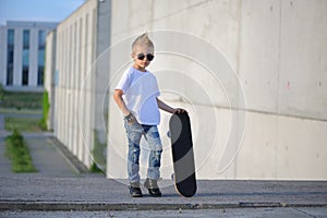 A portrait of defiant boy with skateboard outdoors.
