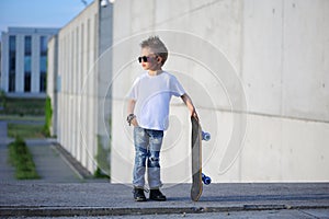 A portrait of defiant boy with skateboard outdoors.