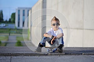 A portrait of defiant boy with skateboard outdoors.