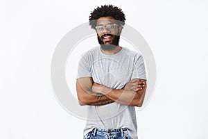Portrait of delighted calm and handsome african american male coworker in glasses with tattoos and pierced nose smiling