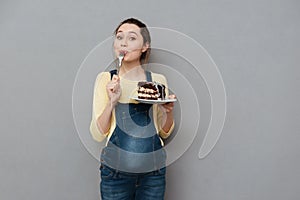 Portrait of a delighted young pregnant woman eating chocolate cake